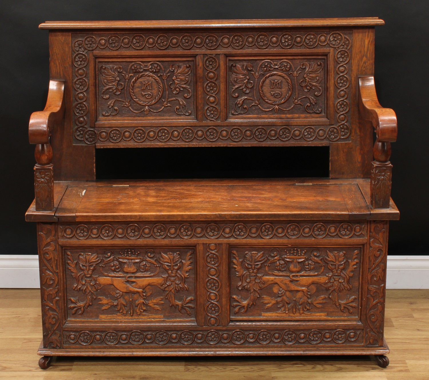 A 17th century style oak box settle or bench, two panel rectangular back initialled MA and carved