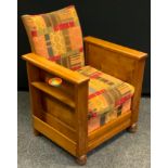 A 1930s Art Deco oak arm chair, each side with magazine holders, the front detaching into a