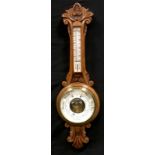 An early 20th century golden oak aneroid barometer thermometer, carved shaped case, 86cm long.