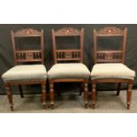 A set of three Victorian chairs, carved top, stuffed over upholstery, turned legs. (3)