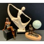 A contemporary bronze colored metal figure, The Risque Bather modeled seated on a marble block base,