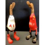 A wooden duck, standing, wearing football shirt, 47cm high; another (2)