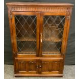 A Priory oak bookcase, rectangular top above a pair of glazed doors enclosing shelves and a pair