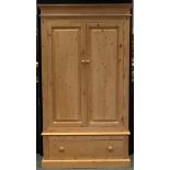 A modern pine double wardrobe, outswept cornice above a pair of cupboard doors enclosing a clothes