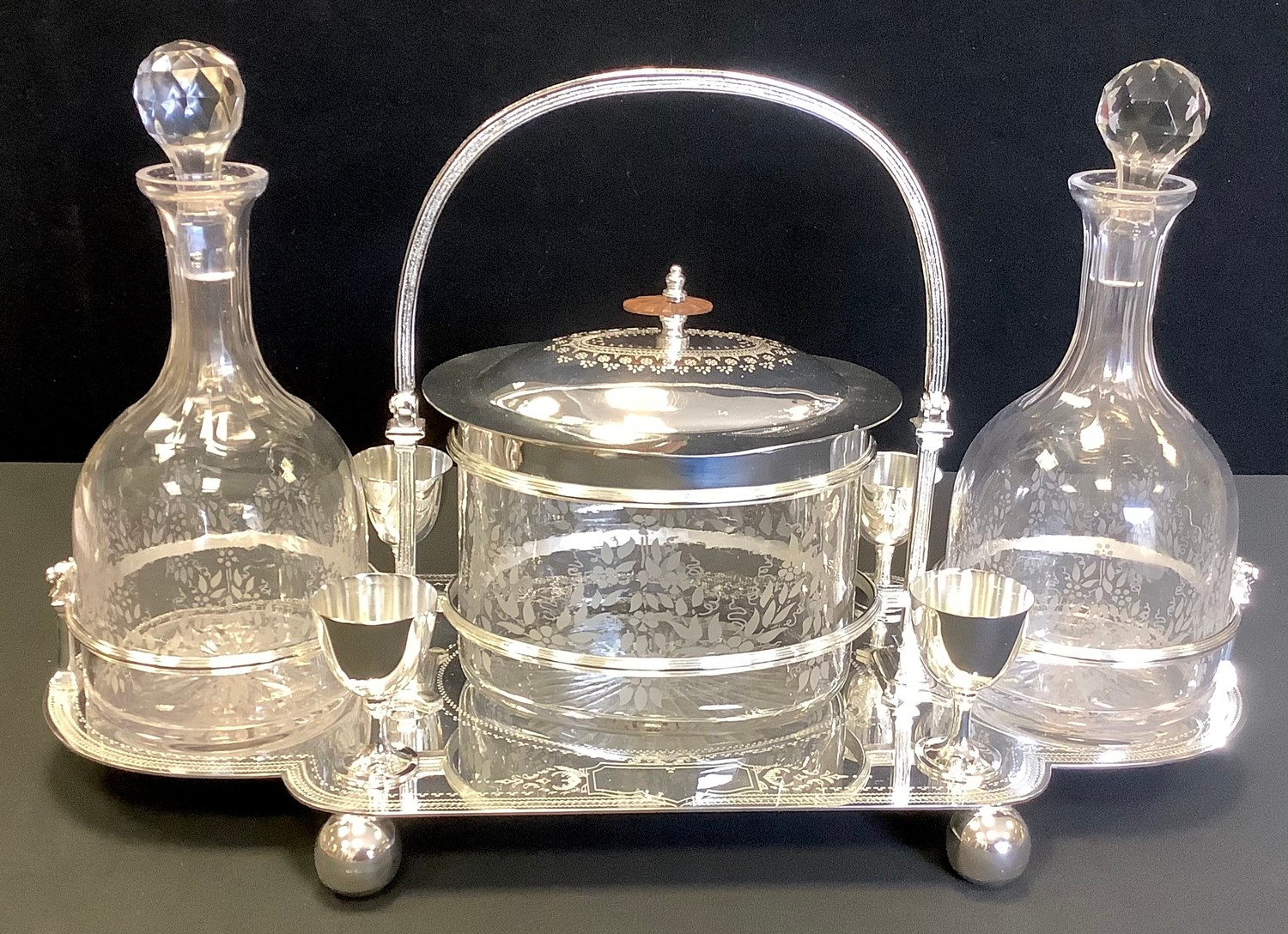 A contemporary silver plated decanter set, with two clear glass decanters, central wafer box, and