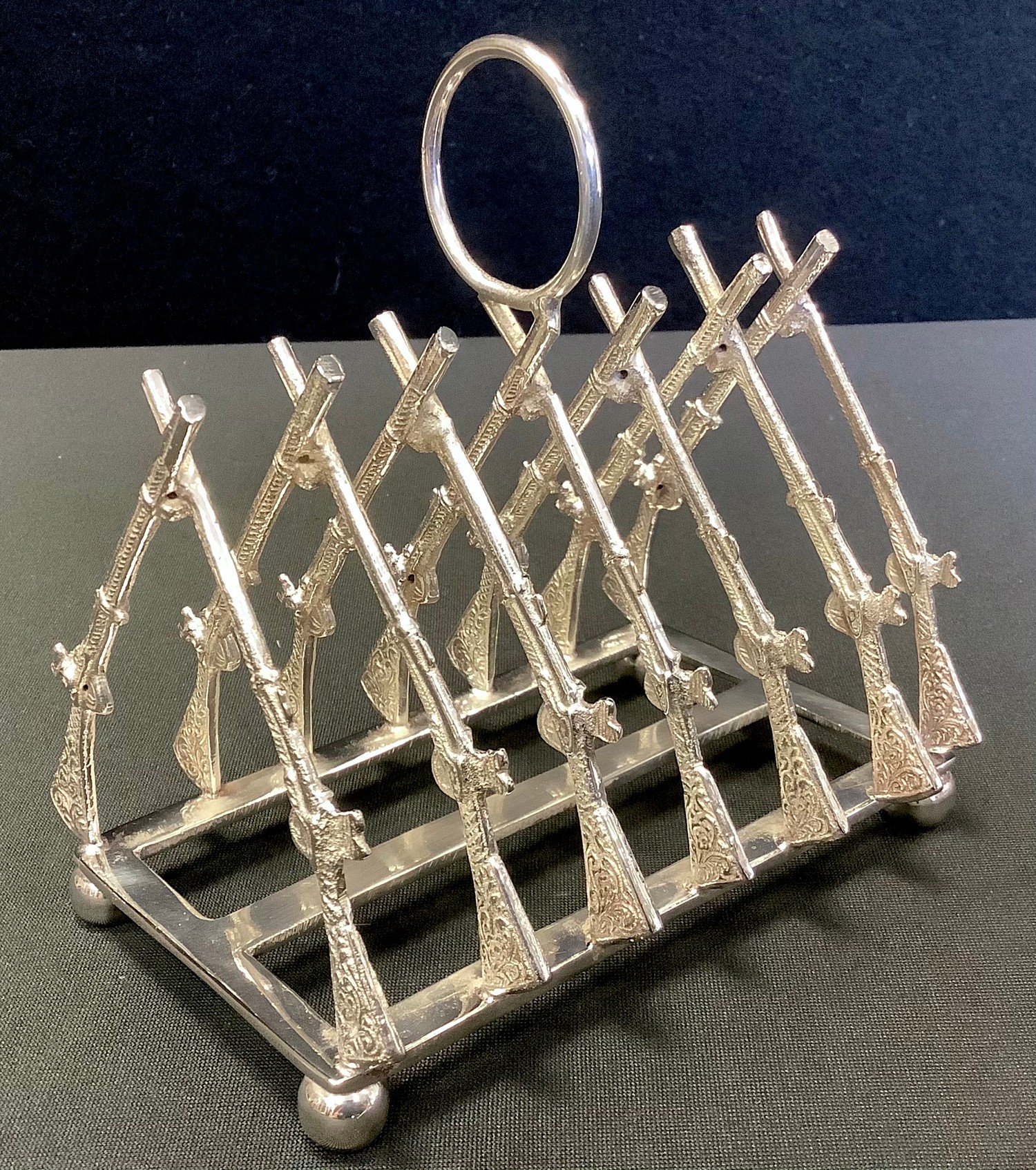 A modern silver plated toast rack, the bars as rifles, 11.5cm wide
