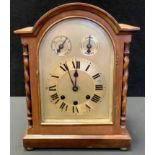 A mahogany dome top mantel clock, arched face, Roman numerals, flanked by barley twist columns,