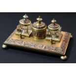 A 19th century copper and brass standish, with cylindrical pounce pot flanked by two square wells,