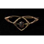 An Arts & Crafts style 9ct gold brooch, the design a triform knotted motif, centred by a claw-set