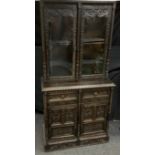 A Jacobean Revival oak bookcase cabinet, a pair of glazed doors enclosing adjustable shelves, the