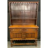 An early 20th century oak dresser, shaped apron above plate racks, the projecting base with two