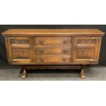A 20th century oak long sideboard, with three long drawers flanked by linen fold panelled doors,