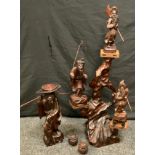 A large carved oriental figural stand, three platforms each mounted with a wooden Warriors, 96cm