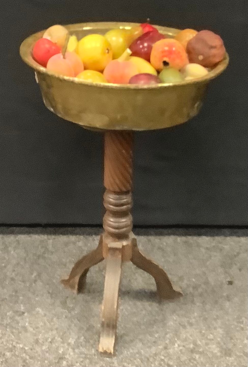 Faux fruit in a brass bowl, on associated torchere stand