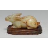 A Chinese russet jade carving, of a seated rabbit, 11cm long, hardwood stand
