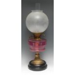 An early 20th century cranberry glass and brass table oil lamp, globular etched glass shade,