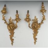 A pair of Louis XV Revival gilt metal two-light wall sconces, cast throughout with scrolling