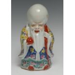 A Chinese polychrome figure, of Shou Lao, he stands, holding a peach, brightly decorated in enamels,