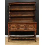 A Jacobean inspired oak dresser, moulded cornice above two plate racks, the projecting base with two