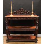 A late Victorian oak three-tier buffet, shaped half gallery carved with a grotesque mask, fruit, C-
