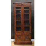 A Jacobean Revival oak library bookcase, oversailing top above a pair of glazed doors enclosing
