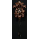 A Black Forest cuckoo clock, carved with a stag head and hanging game, 54cm high