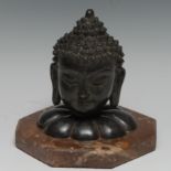 A Chinese dark patinated bronze model, the head of Buddha, mounted for display with fluted socle and