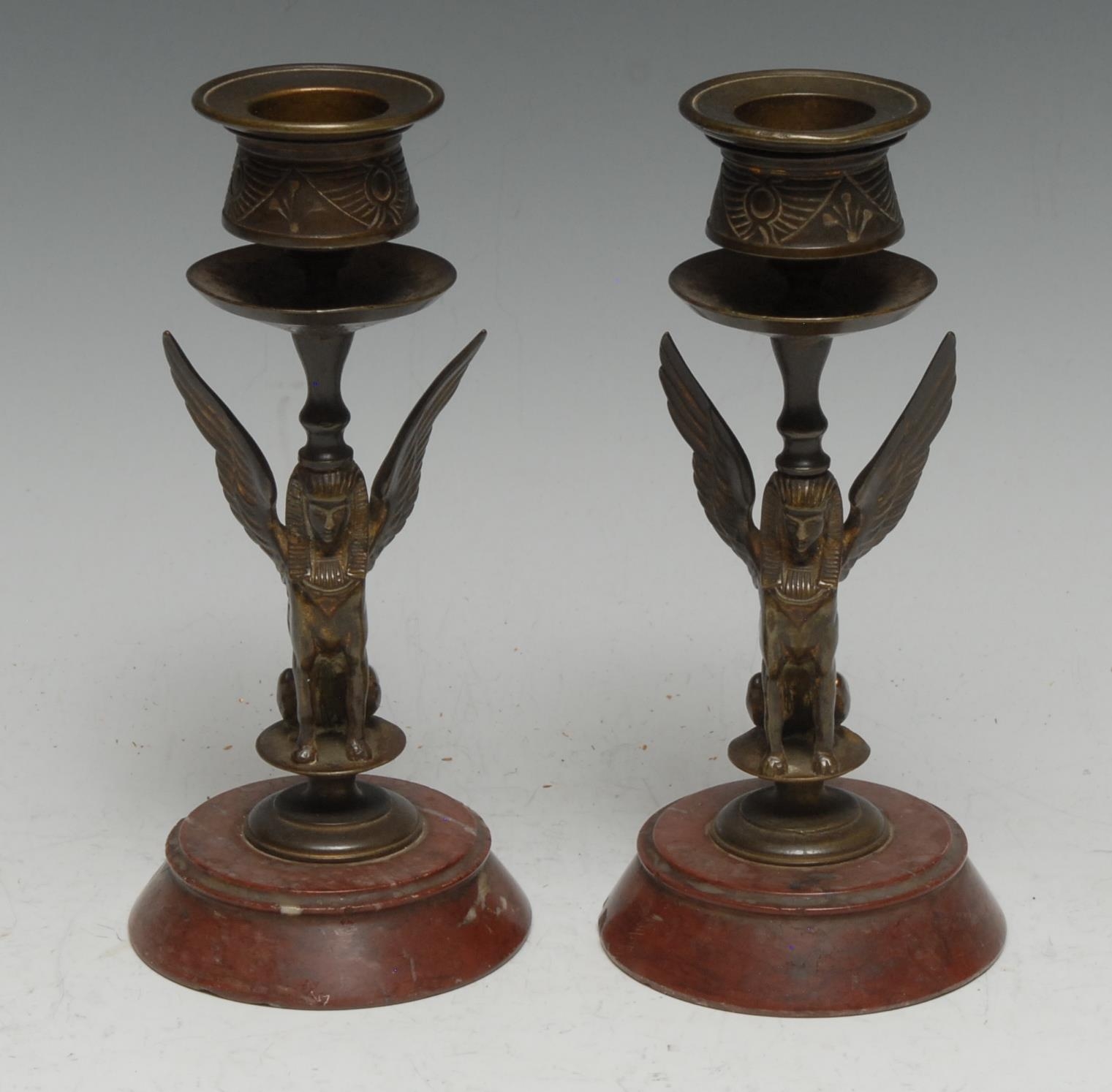 A pair of 19th century Egyptian Revival gilt bronze candlesticks, each cast as a seated sphinx,