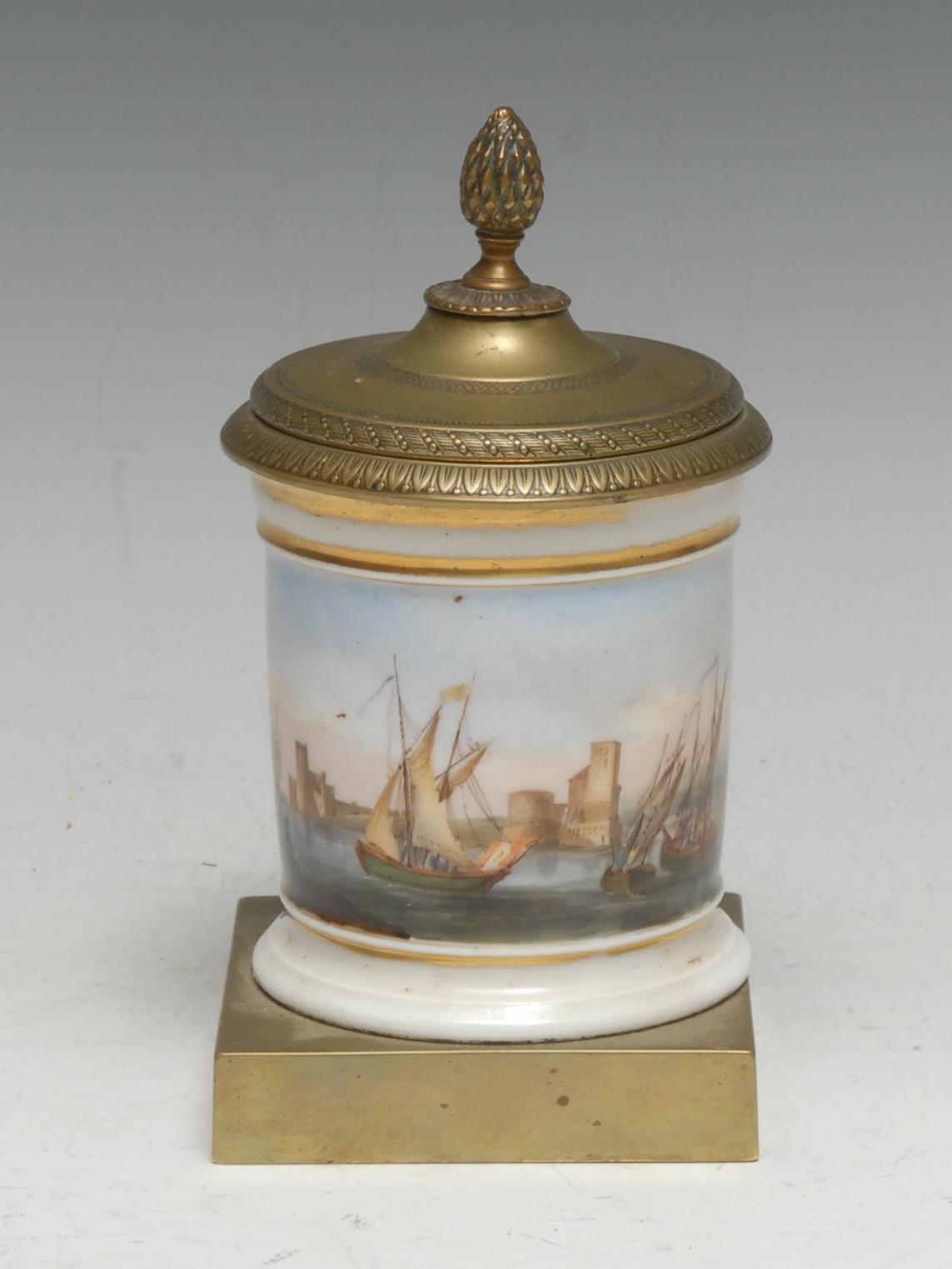 A French Empire porcelain and brass desk inkwell, painted with a maritime scene, the cover with pine