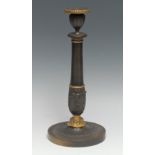 A French Empire parcel-gilt and brown patinated bronze table candlestick, cast with bands of