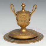 A 19th century gilt brass urnular inkwell, hinged cover, lofty scroll handles terminating in leafy