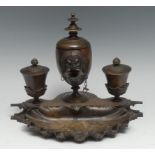 A 19th century Grand Tour brown patinated bronze ink stand, the central lamp cast with an Egyptian