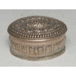A Burmese/Tibetan silver coloured metal navette shaped betel box, chased throughout with stylised