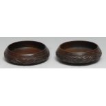 Treen - a pair of 19th century mahogany wine coasters, carved with a band of leafy branches, 13cm