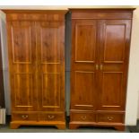 A near pair of reproduction yew wood double wardrobes, outswept cornice above a pair of panel