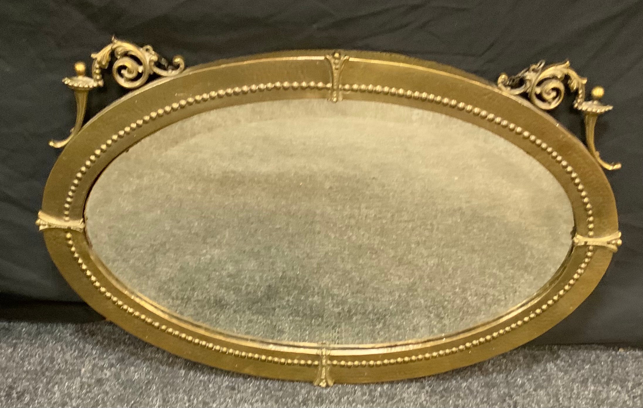 A Neoclassical brass oval wall mirror, beveled plate, 50cm x 78cm.