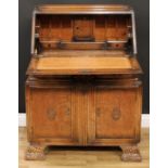 An Art Deco oak bureau, fall front enclosing a tooled and gilt writing surface, small door, pen