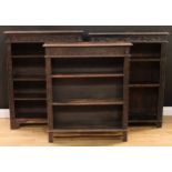 A late Victorian ebonised oak open bookcase, carved with scrolling acanthus and floral lunettes,