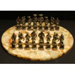 A novelty cast metal chess set as continental figures in 16th century fashion, a circular onyx chess