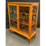 An Arts & Crafts light oak two door display cabinet, stained leaded glass doors, 115cm high, 92cm