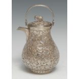 An Indian silver ovoid water jug, chased overall with scrolling foliage, swing handle, elephant