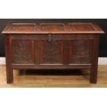 A late 17th century oak three-panel blanket chest, hinged cover, the front carved with leafy