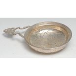 An 18/19th century silver coloured metal orange strainer, shaped and pierced lug handle, 11cm