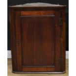 A George III oak splay fronted wall hanging corner cupboard, moulded cornice above a rectangular