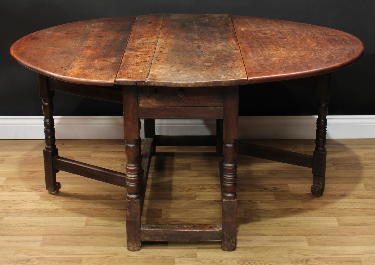 A 17th century oak gateleg table, oval top with fall leaves above a frieze drawer, turned and