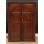 A large George III oak wall hanging corner cupboard, moulded cornice above a pair of arched panel