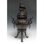 A large Japanese brown patinated bronze tripod koro, the domed cover crested by a peacock, cast