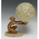 An Art Deco gilt-patinated, glass and onyx table-lamp, as a scantily clad maiden holding a marbled
