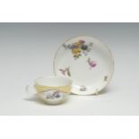 A Meissen teacup and saucer, the cup with two shaped floral panels, on a yellow ground, the saucer