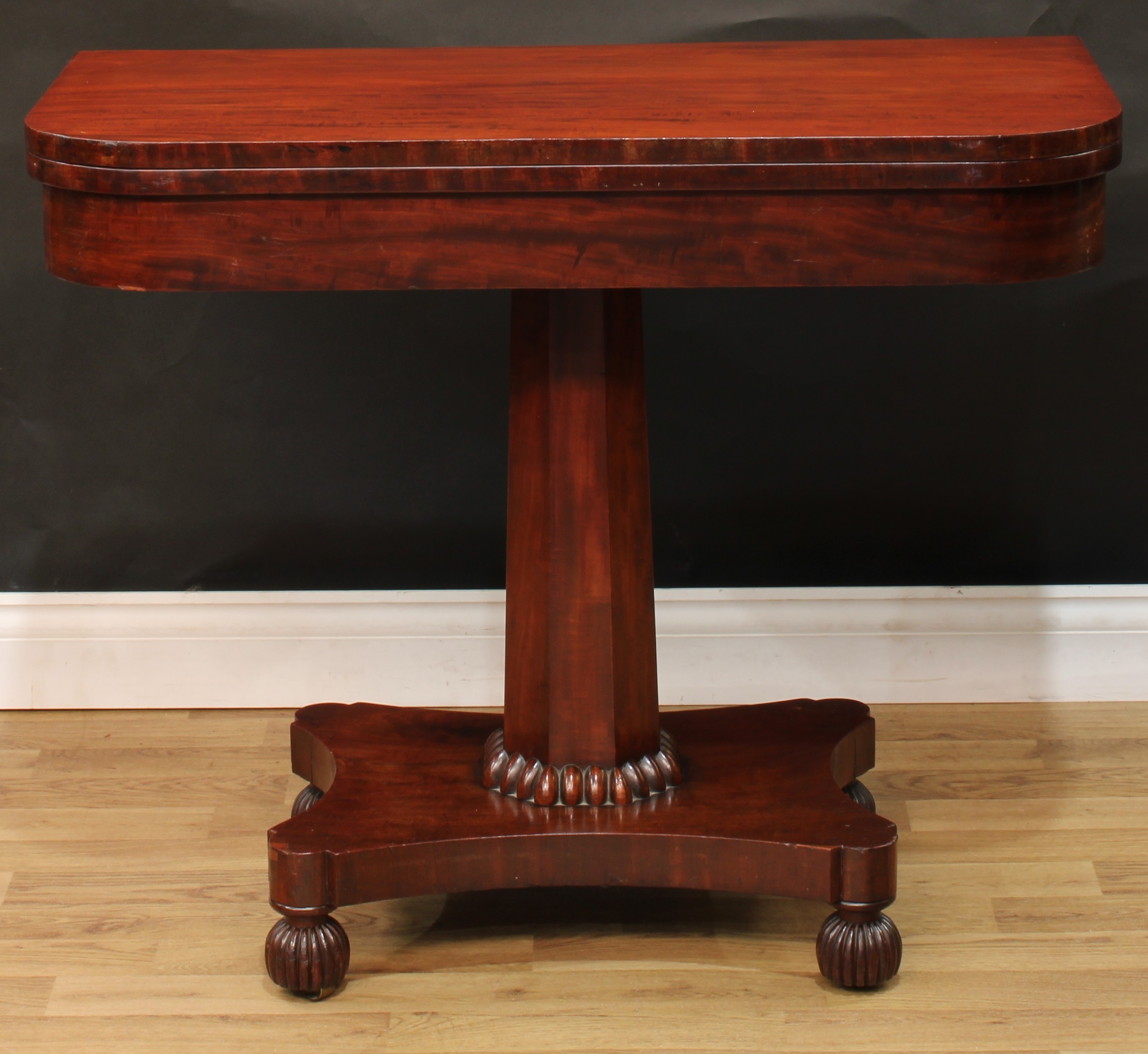 A William IV mahogany card table, hinged top, spreading octagonal column, egg socle, hipped